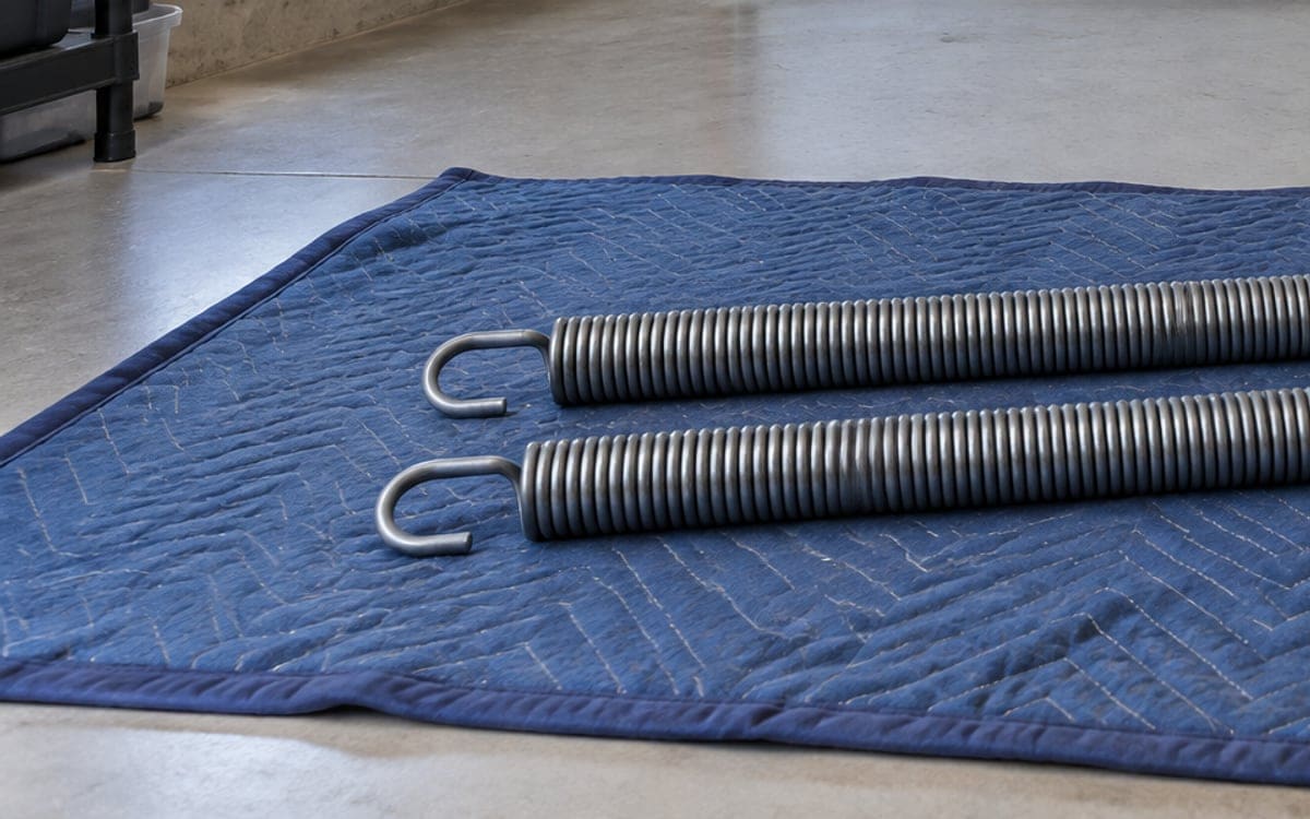 A new pair of extension springs lying on a moving blanket, ready for a garage door spring repair.