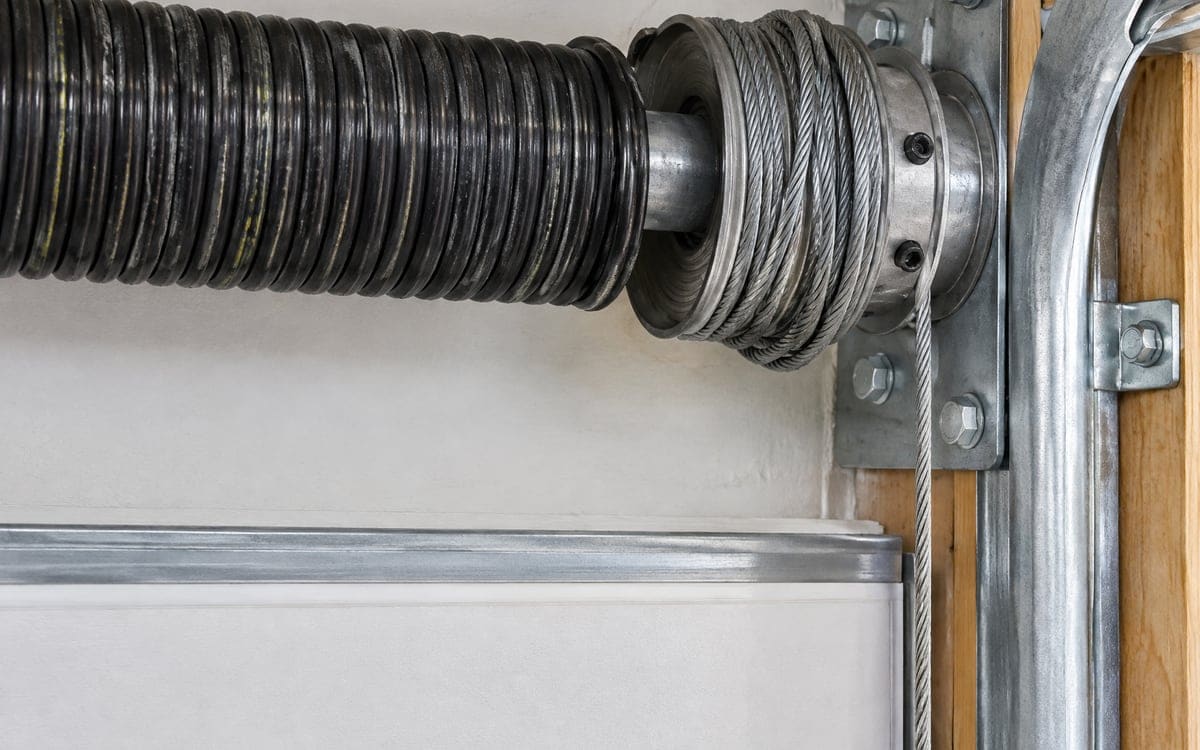 A lift cable wound loose and out of its grooves on the cable drum at the end of the torsion shaft, a job for garage door cable repair.