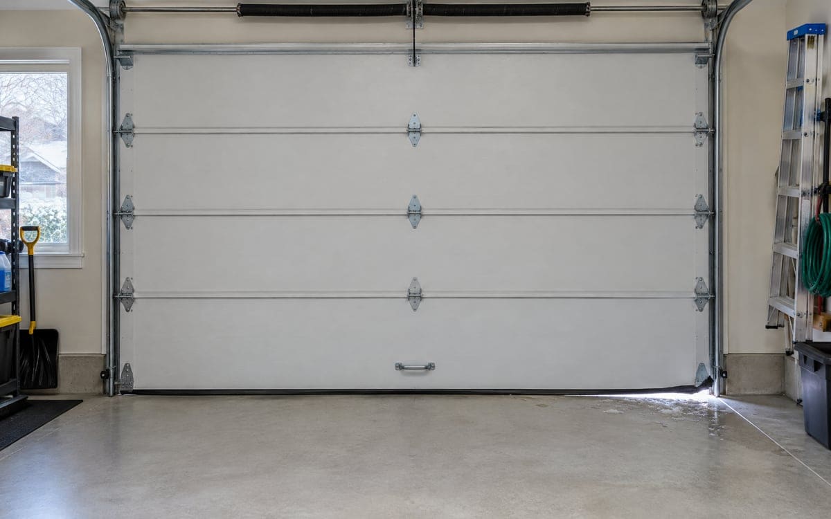 Daylight showing under one corner of a closed door, a sign the garage door bottom seal has worn through.