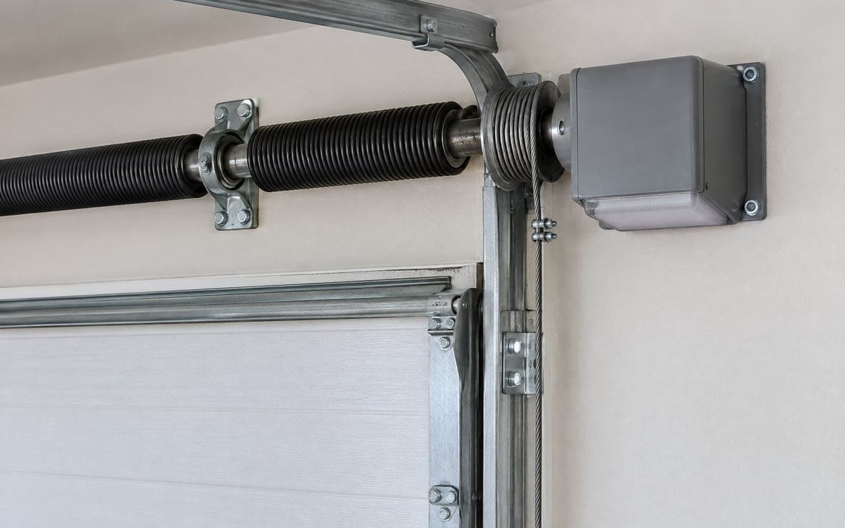 A wall-mount opener bolted beside the end of the torsion shaft, an option in garage door opener installation when the ceiling stays clear.